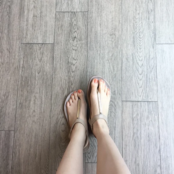 Vrouwelijke voet in sandalen op de grond achtergrond — Stockfoto