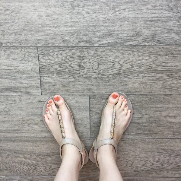Vrouwelijke voet in sandalen op de grond achtergrond — Stockfoto