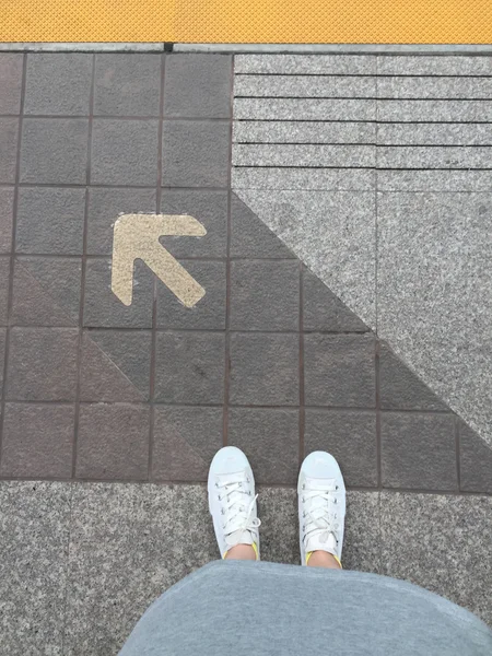 Female Feet in White Sneakers And Arrow Heading Forward — Stock Photo, Image