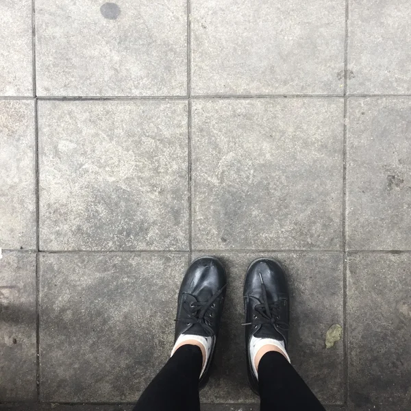 Selfie Feet portant une chaussure noire pour femme sur fond de sol — Photo