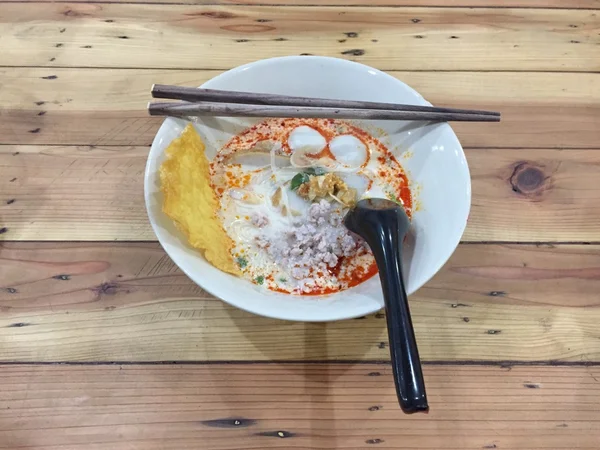 Fideos Tom Yum con cerdo, Fideos tailandeses picantes sobre fondo de madera —  Fotos de Stock