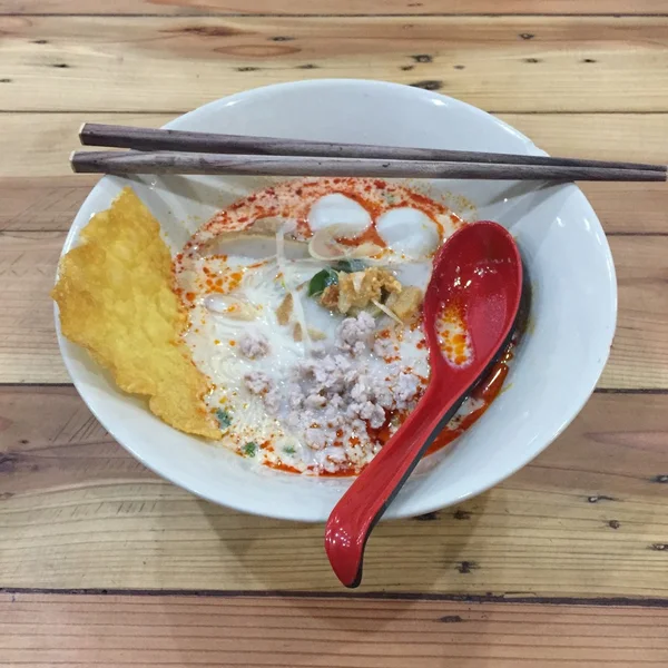 Fideos Tom Yum con cerdo, Fideos tailandeses picantes sobre fondo de madera —  Fotos de Stock