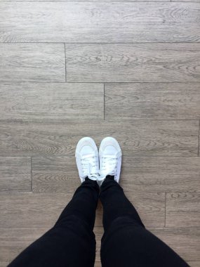 Spor ayakkabı beyaz ve kot kız bacaklar ahşap arka plan üzerinde siyah 