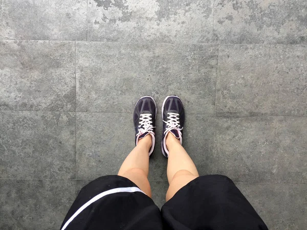 Běžecké boty. Barefoot běžecká obuv Closeup. Žena nosí sportovní boty na pozadí dlaždic — Stock fotografie