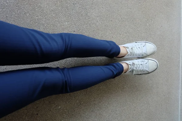 Módní mladá žena v modrých kalhotách a bílé tenisky na ulicích — Stock fotografie