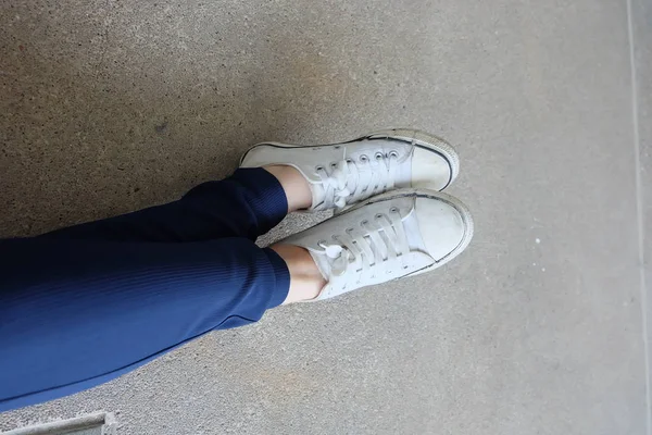 Módní mladá žena v modrých kalhotách a bílé tenisky na ulicích — Stock fotografie