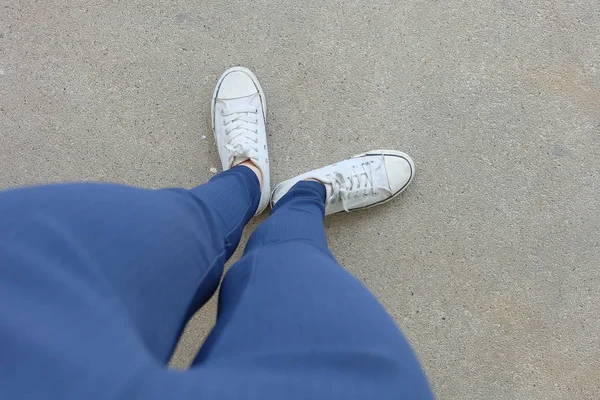 Moda mujer joven en pantalones vaqueros azules y zapatillas blancas en las calles —  Fotos de Stock