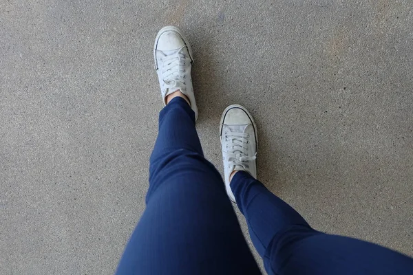 Mode junge Frau in blauen Jeans und weißen Turnschuhen auf der Straße — Stockfoto