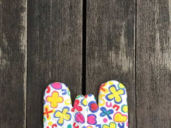 Küche schützende bunte Blume Handschuhe auf Holz Hintergrund — Stockfoto