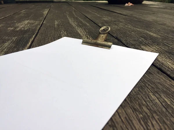 Binder Clip and Stack of Papers on Wooden Background