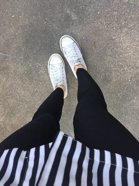 床の背景にスニーカー (白靴) で若いファッション女性の足 — ストック写真