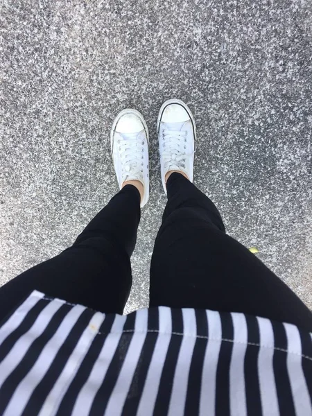 Νέοι μόδας γυναικεία πόδια με πάνινα παπούτσια (λευκά παπούτσια) σε φόντο δαπέδου — Φωτογραφία Αρχείου