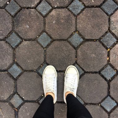 Genç kadının bacakları ile spor ayakkabı, döşeme arka planı beyaz ayakkabılarla moda 