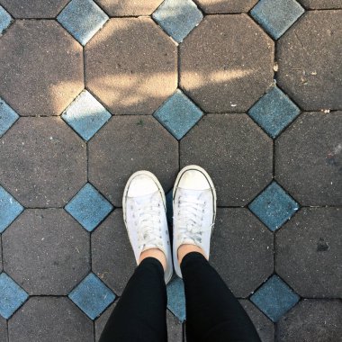 Genç kadının bacakları ile spor ayakkabı, döşeme arka planı beyaz ayakkabılarla moda 