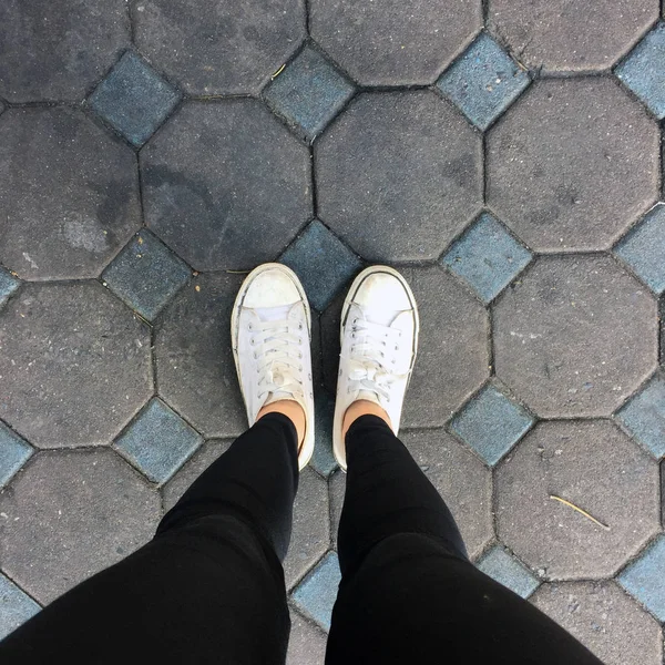 Móda pro mladé ženské nohy s tenisky, bílé boty na pozadí dlaždic — Stock fotografie