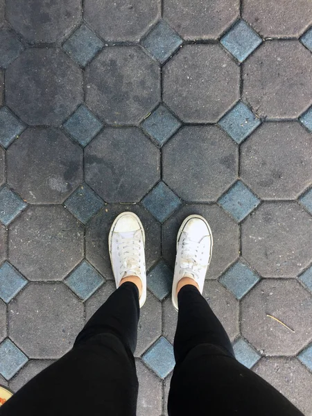 Jonge mode vrouw poten met Sneakers, witte schoenen op tegel achtergrond — Stockfoto