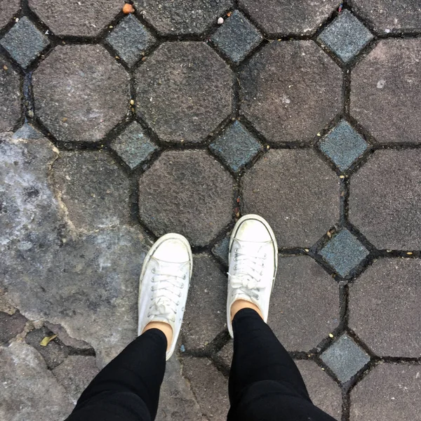 Piernas de mujer de moda joven con zapatillas, zapatos blancos en el fondo del azulejo —  Fotos de Stock