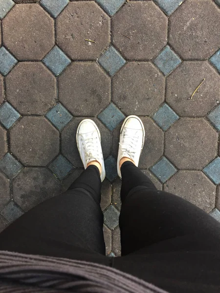 Genç kadının bacakları ile spor ayakkabı, döşeme arka planı beyaz ayakkabılarla moda — Stok fotoğraf