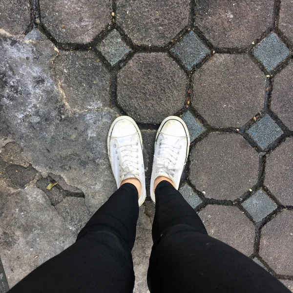 Piernas de mujer de moda joven con zapatillas, zapatos blancos en el fondo del azulejo —  Fotos de Stock