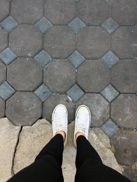 Gambe da donna di moda giovane con scarpe da ginnastica, Scarpe bianche su sfondo piastrelle — Foto Stock