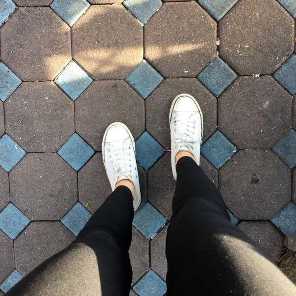 Piernas de mujer de moda joven con zapatillas, zapatos blancos en el fondo del azulejo —  Fotos de Stock