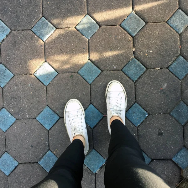 Piernas de mujer de moda joven con zapatillas, zapatos blancos en el fondo del azulejo —  Fotos de Stock