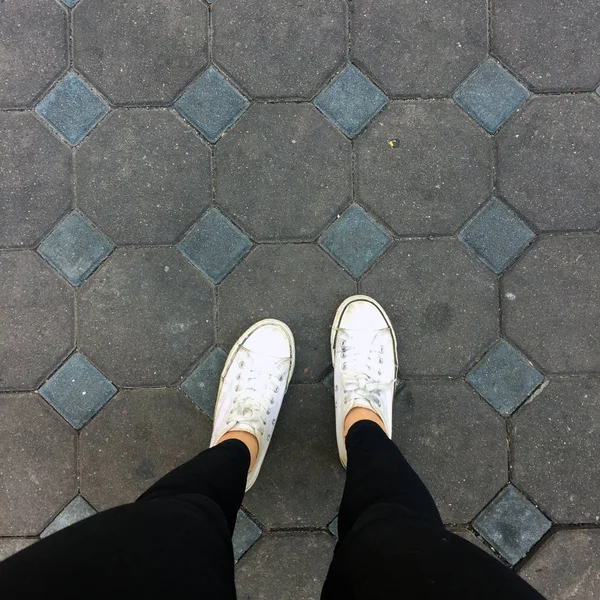 年轻时尚女性的腿部配运动鞋，白色的鞋子上平铺背景 — 图库照片