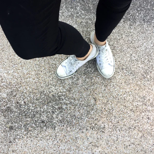 Ноги молодой женщины моды с кроссовками, белые туфли на фоне пола — стоковое фото