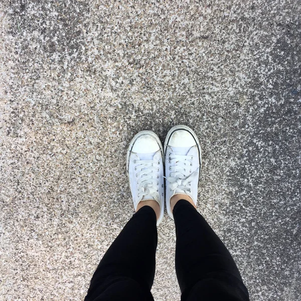 Piernas de mujer de moda joven con zapatillas, zapatos blancos en el fondo del piso — Foto de Stock