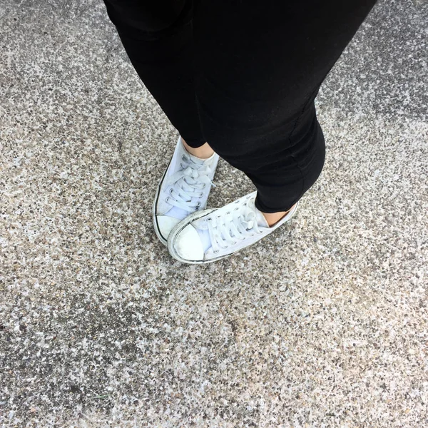 Pernas de mulher de moda jovem com tênis, sapatos brancos no chão de fundo — Fotografia de Stock