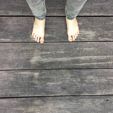 Kadının kot pantolon ve ahşap arka plan üzerinde çıplak ayak 