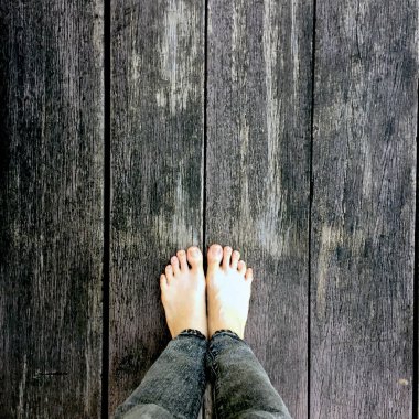 Kadının kot pantolon ve ahşap arka plan üzerinde çıplak ayak 