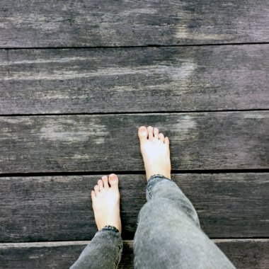 Kadının kot pantolon ve ahşap arka plan üzerinde çıplak ayak 