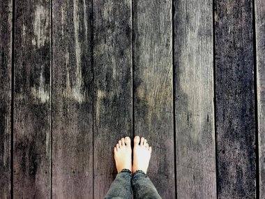 Kadının kot pantolon ve ahşap arka plan üzerinde çıplak ayak 