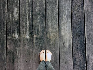 Kadının kot pantolon ve ahşap arka plan üzerinde çıplak ayak 