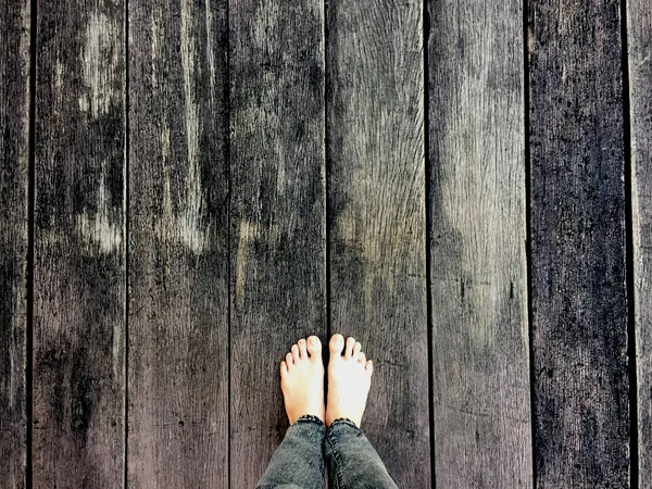 Kadının kot pantolon ve ahşap arka plan üzerinde çıplak ayak 