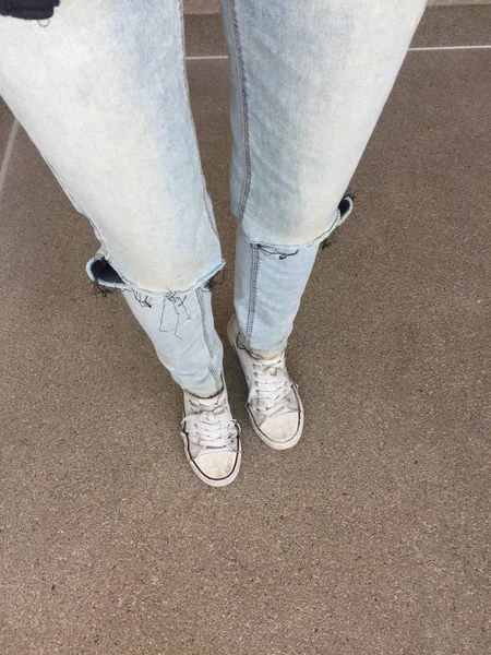 Kvinnans ben i blå Jeans och vita Sneakers på golvet — Stockfoto
