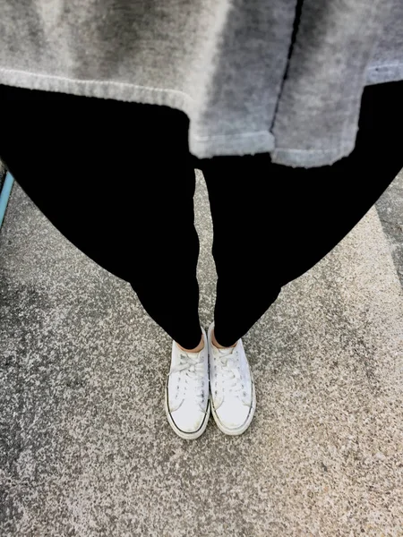 Νέοι μόδας γυναικεία πόδια με αθλητικά παπούτσια, παπούτσια λευκό σε φόντο δαπέδου — Φωτογραφία Αρχείου