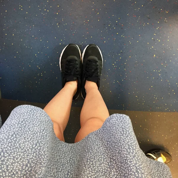 Образ модницы на улице: женские ноги, синее платье и черные кроссовки — стоковое фото