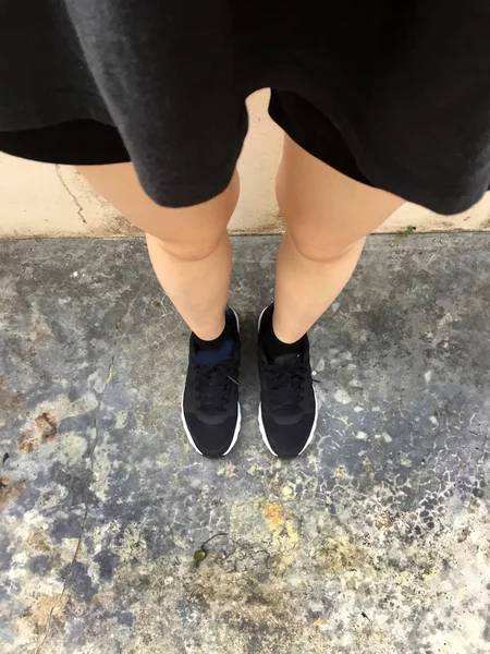 床の背景に黒のスニーカーで女性の足 — ストック写真