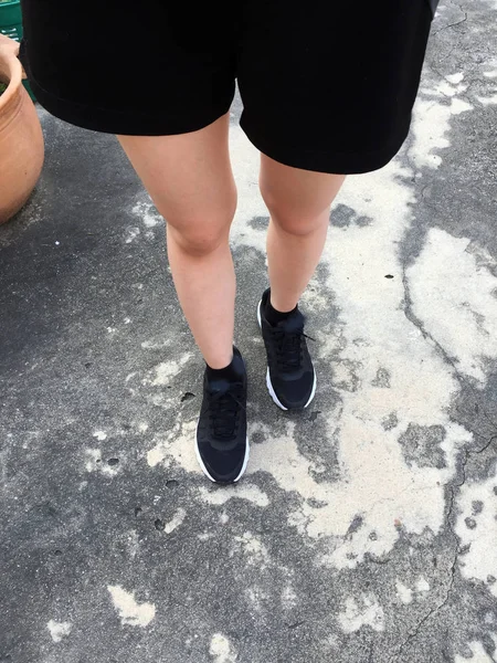 Женские ноги в черных кроссовках на фоне пола — стоковое фото