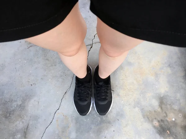 Kobiece stopy w czarne sneakers na podłodze tło — Zdjęcie stockowe