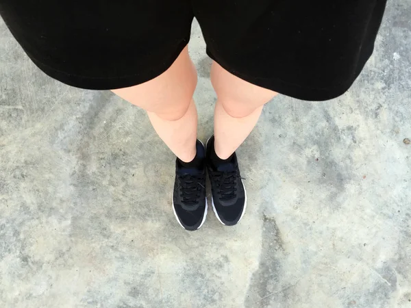 Pieds féminins en Sneakers noires sur fond de sol — Photo