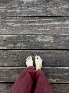 Kadının Lay pantolon ve ahşap arka plan üzerinde çıplak ayak 