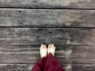 Kadının Lay pantolon ve ahşap arka plan üzerinde çıplak ayak 