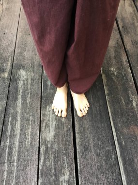 Kadının Lay pantolon ve ahşap arka plan üzerinde çıplak ayak 