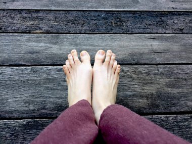 Kadının Lay pantolon ve ahşap arka plan üzerinde çıplak ayak 