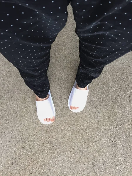Vrouw dragen witte Slippers permanent op de achtergrond van de grond — Stockfoto