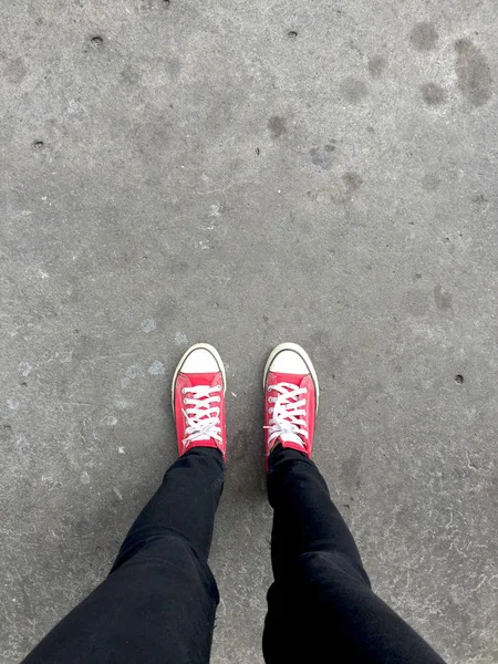 Fötter från ovanstående koncept, Teenage Person i röda Sneakers stående på marken bakgrund — Stockfoto