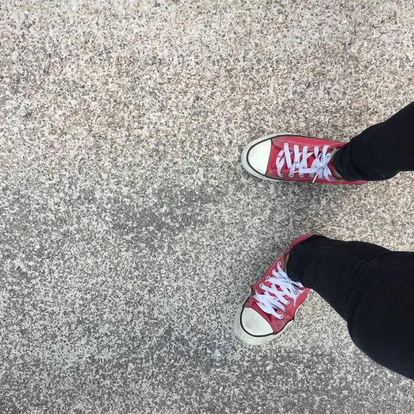 Πόδια ψηλά έννοια, εφηβικό πρόσωπο σε κόκκινο πάνινα παπούτσια που στέκεται στο έδαφος φόντο — Φωτογραφία Αρχείου